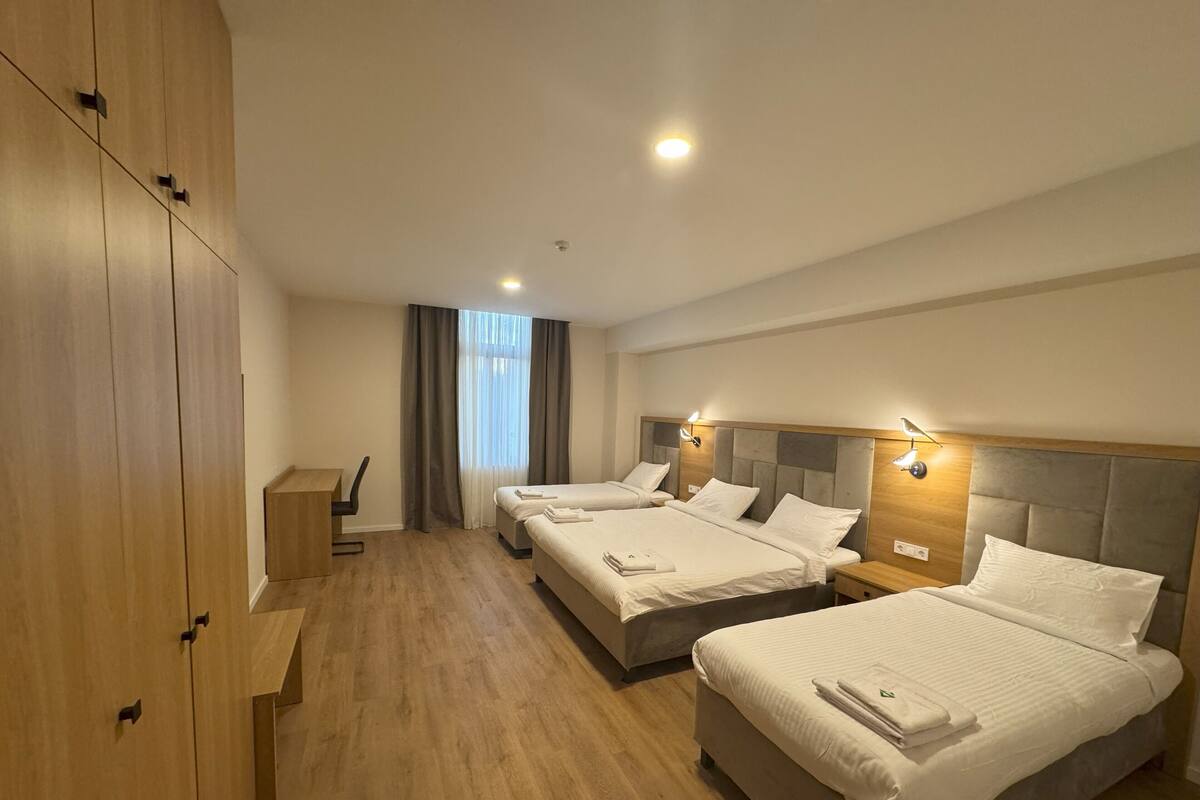 A hotel room with two beds, a desk, and a wardrobe.