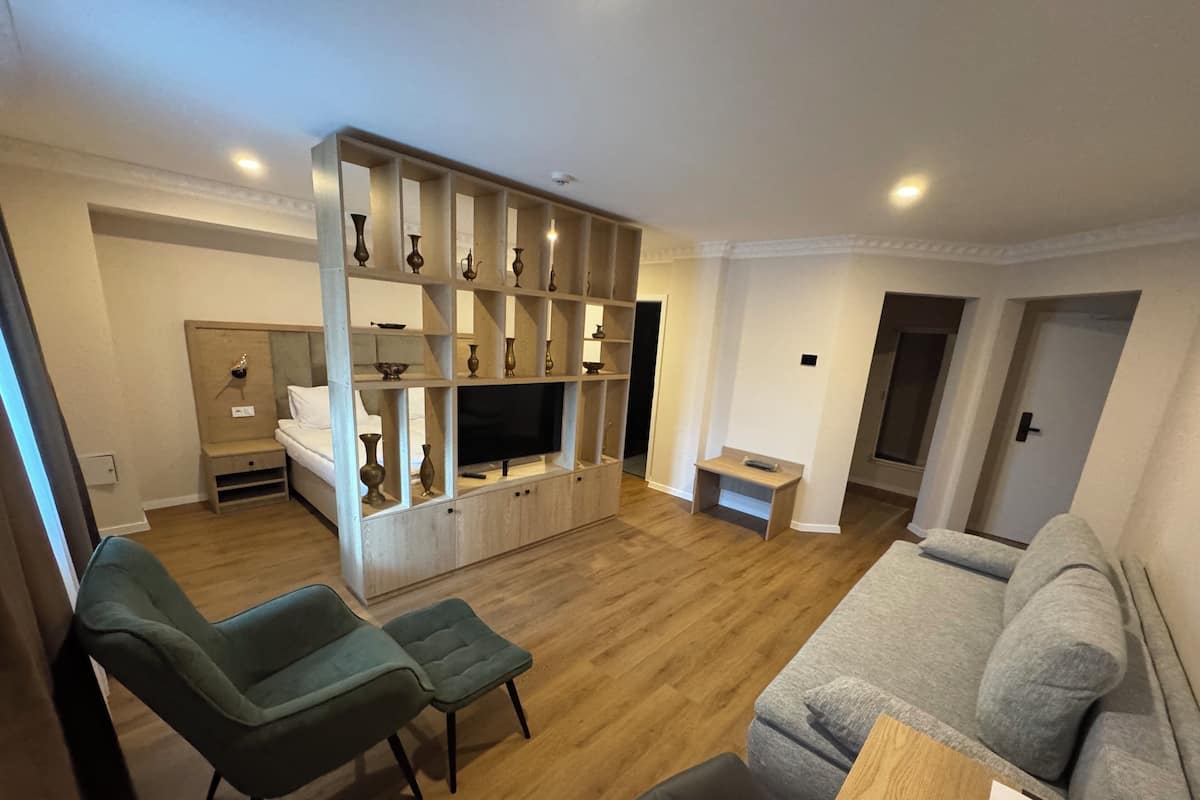 A living room with a sofa, two armchairs, a TV, and a wooden entertainment unit with shelves.