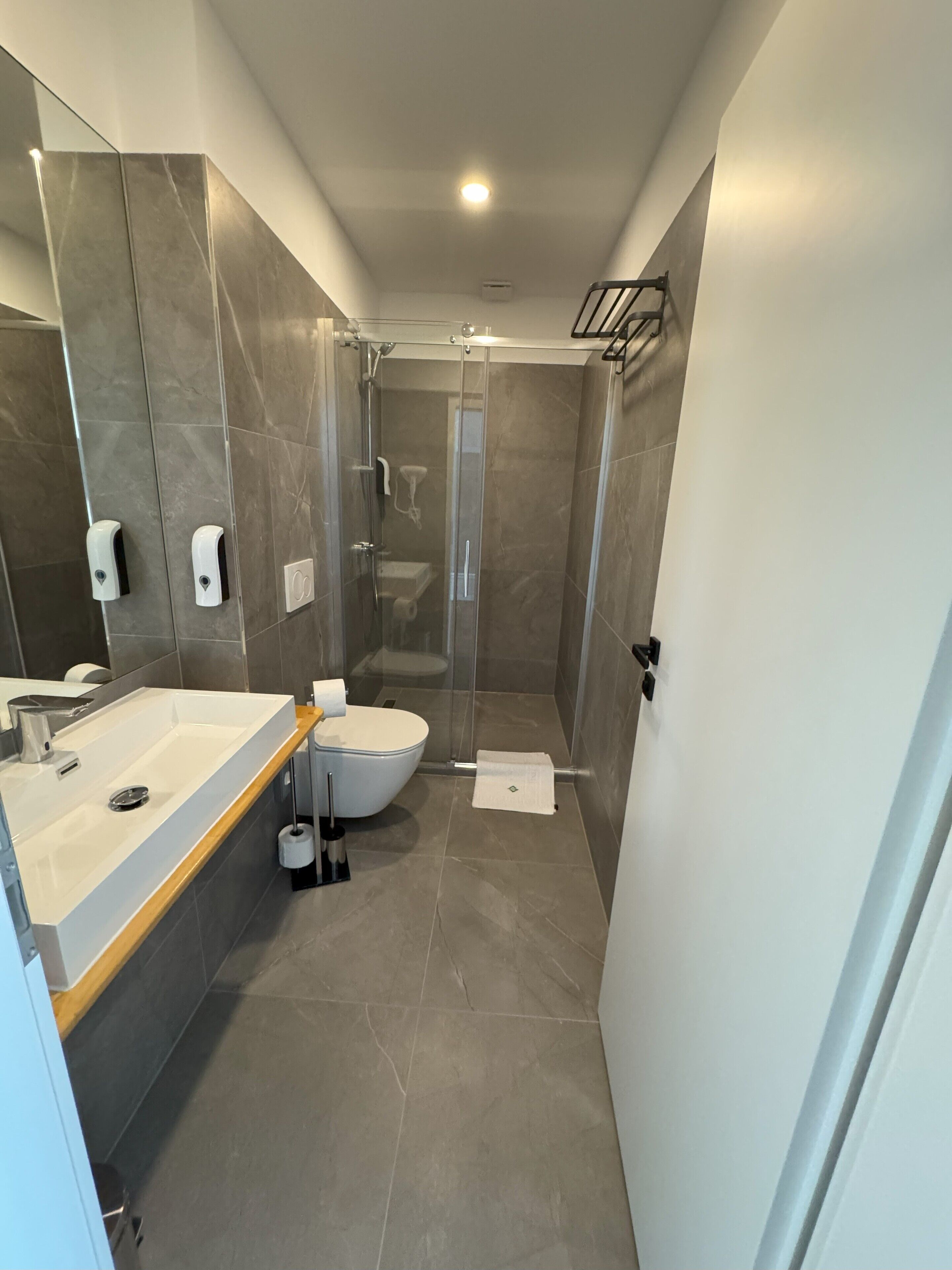 Un baño moderno con un espejo grande, lavamanos, inodoro y cabina de ducha.