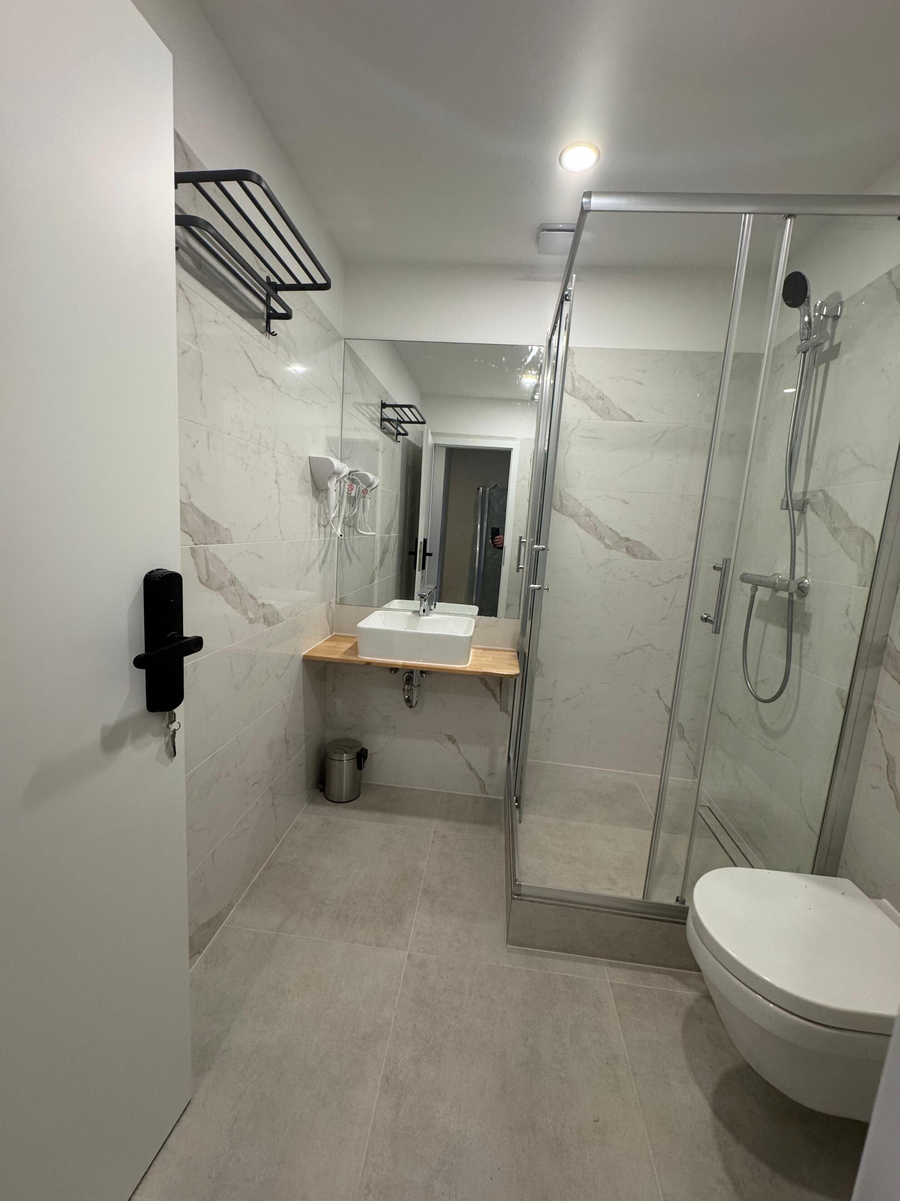 A modern bathroom with a glass-enclosed shower, a white toilet, and a vanity with a sink.