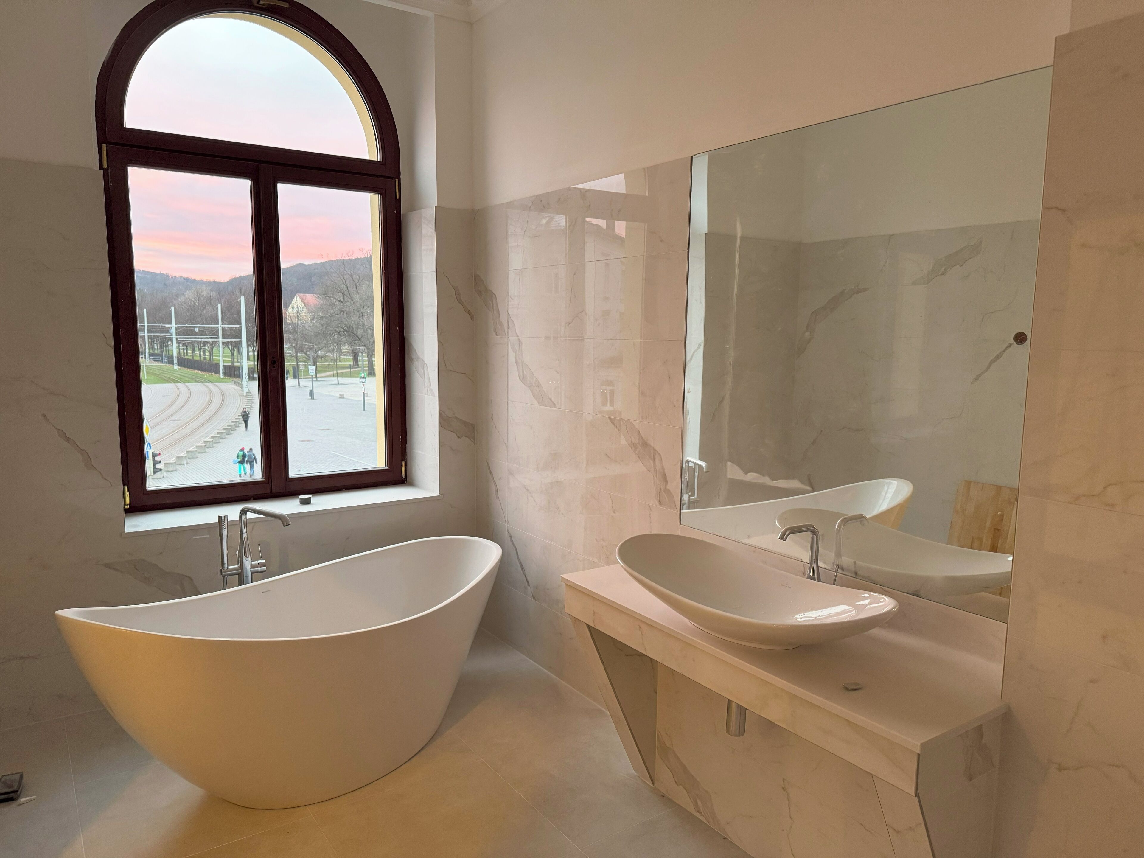 A modern bathroom with a freestanding bathtub, a sink, and a large mirror.