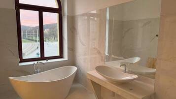 A modern bathroom with a freestanding bathtub, a sink, and a large mirror.