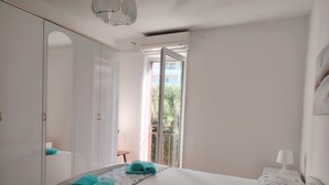 Une chambre avec un grand lit, une armoire, un miroir, une fenêtre et un balcon.
