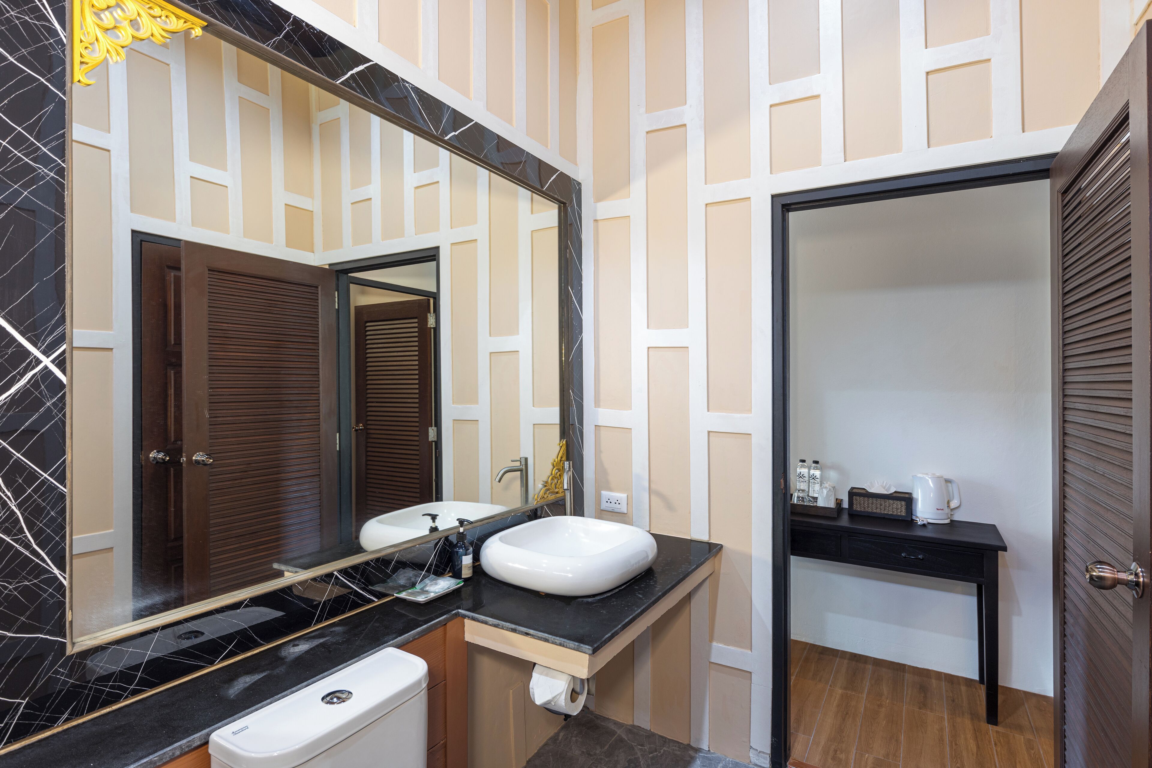 A bathroom with a black marble sink, a mirror, and a wooden door.