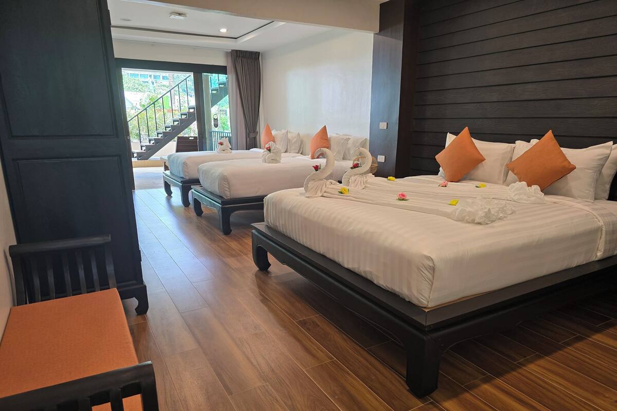 A hotel room with two beds, a wooden floor, and a view of the outside.