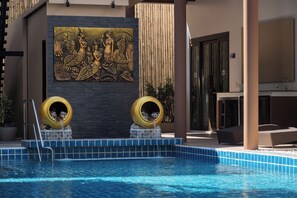 A swimming pool with two yellow pet activity tunnels, a mural, and a lounge area with a view of the pool. - Blue Palm Residence Kata (Karon)