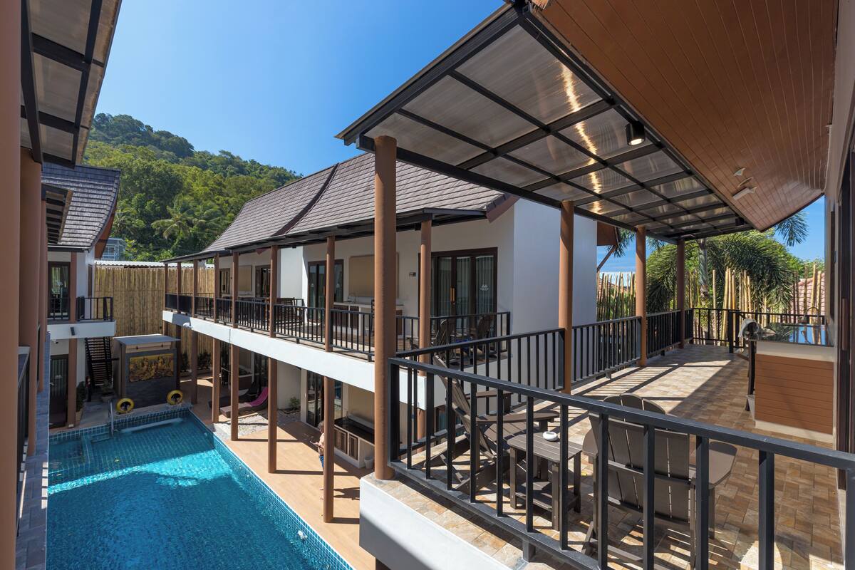 A poolside area with a covered seating area, a pool, and a view of the surrounding landscape.