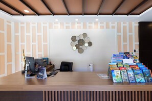 A reception desk with a computer, a printer, and a magazine rack. - Blue Palm Residence Kata (Karon)