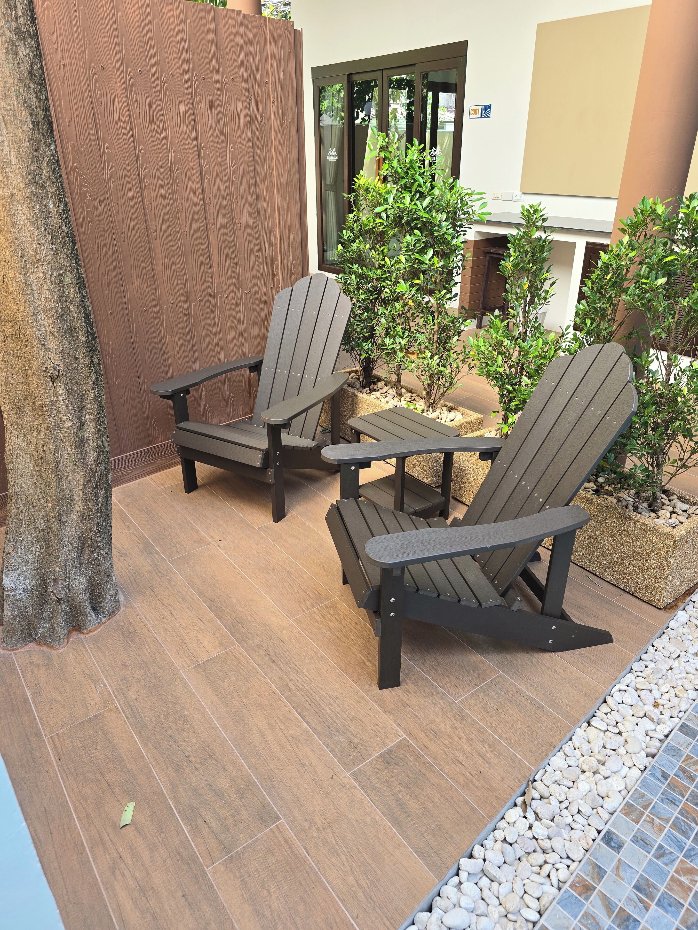 A patio area with two Adirondack chairs, a small table, and a potted plant.