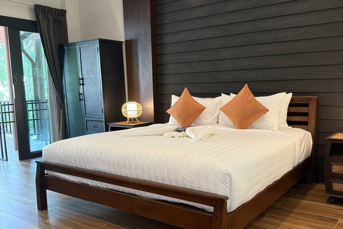 A modern bedroom with a wooden bed, dark wall paneling, and a wooden floor.