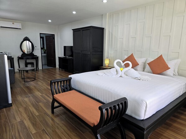 Une chambre d’hôtel avec un grand lit, un bureau, une armoire et un miroir.