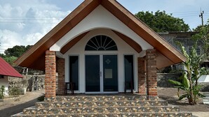 A building with a pitched roof, brick columns, and a set of stone steps leading to a glass door entrance. - La Seahorse Homestay (Sebung)