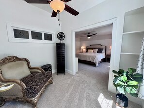 A bedroom with a bed, a nightstand, a dresser, a ceiling fan, and a potted plant. - Swim Spa + Hot Tub, Gazebo, BBQ Grill, 6 Bedrooms (Beaverton)
