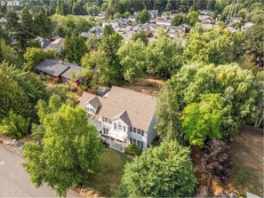An aerial view of a residential area with a large house surrounded by trees and other houses. - Swim Spa + Hot Tub, Gazebo, BBQ Grill, 6 Bedrooms (Beaverton)