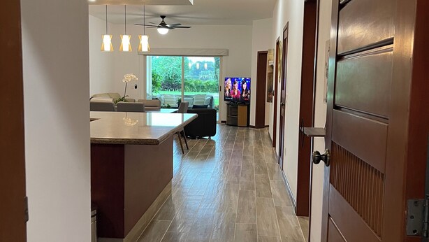 A modern kitchen with a dining area, a TV, and a view of the outdoors. - Poolside Condo, El Tigre. Beautiful (Nuevo Vallarta)