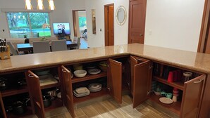 A kitchen with a granite countertop, wooden cabinets, and a dining area with a TV. - Poolside Condo, El Tigre. Beautiful (Nuevo Vallarta)