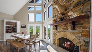 Un amplio comedor con chimenea de piedra, muebles de madera y vistas al exterior.