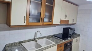 Una cocina con dos fregaderos, un microondas y armarios de madera con puertas de cristal.