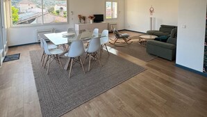 Een ruime woonkamer met een eettafel, stoelen, een bank en een televisie.