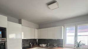 Een moderne keuken met witte kasten, een houten aanrechtblad en een inbouwoven.