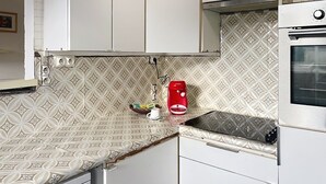 A compact kitchen with patterned backsplash, a Bosch coffee maker, and a built-in oven.