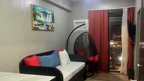 Un espacio habitable compacto con un sofá, una mesa de comedor, una silla colgante y un cuadro en la pared.
