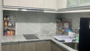 Una cocina con gabinetes blancos, encimera de mármol y pileta de acero inoxidable.