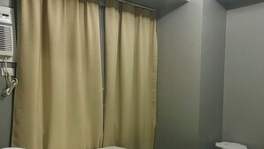 Un dormitorio con cama, cortinas, mesita de noche y aire acondicionado instalado en la pared.