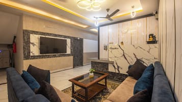 Una sala de estar moderna con un conjunto de sofá, una mesa de centro, un televisor y un mostrador de recepción.