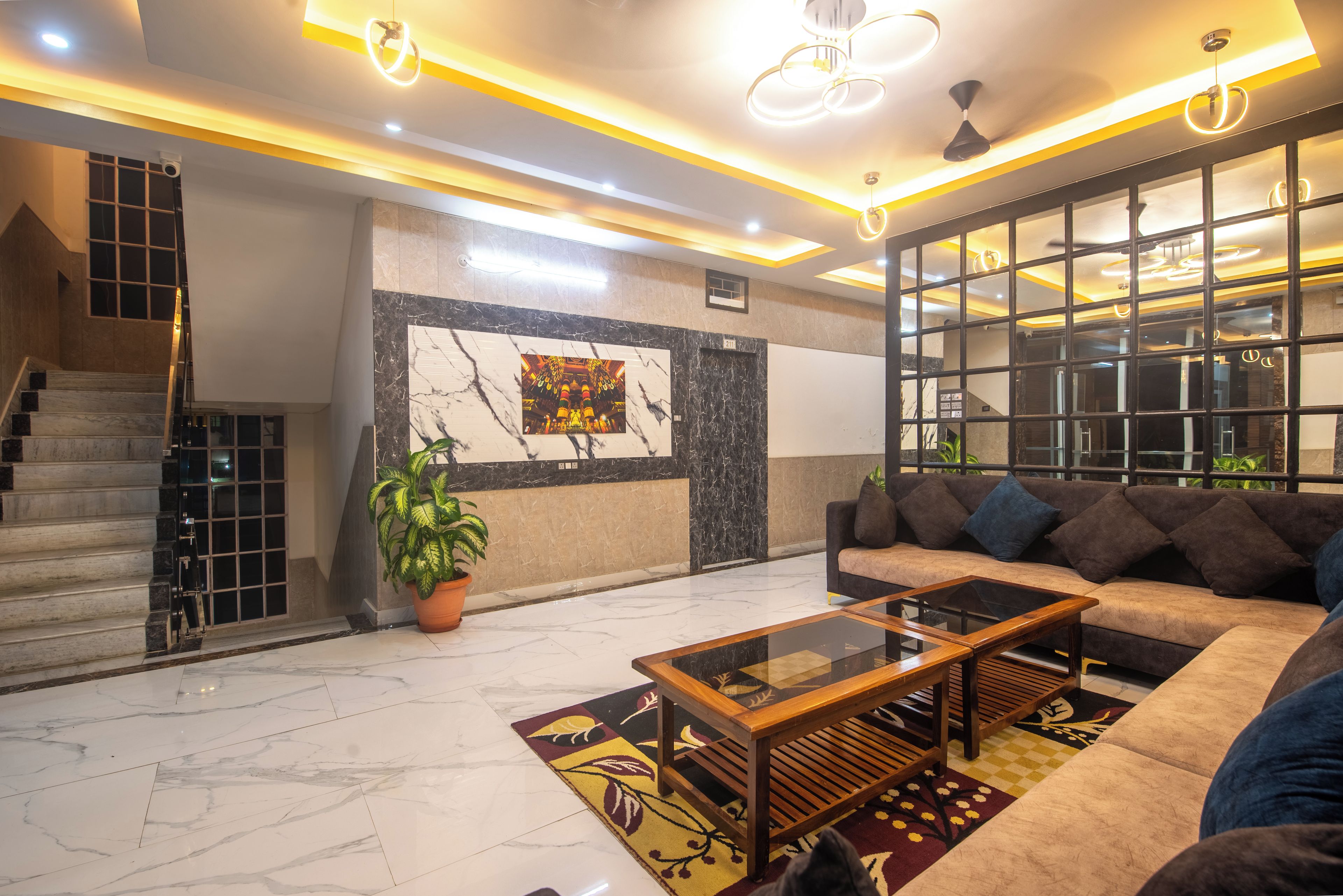 A modern lobby with a marble floor, a sofa, a coffee table, a staircase, and a large window.