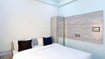 Ein modernes Schlafzimmer mit einem großen Bett, einem Nachttisch und einem wandmontierten Spiegel.