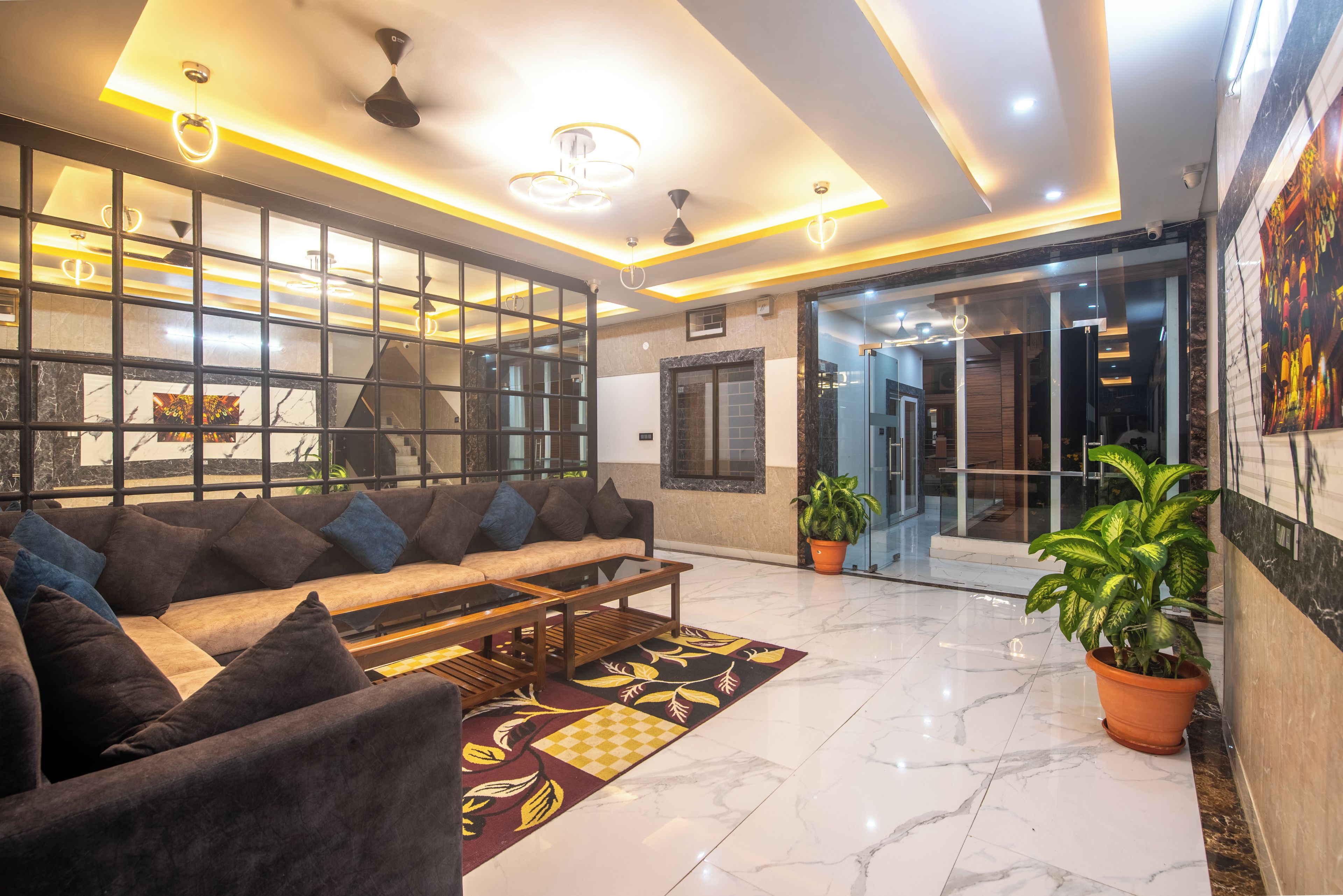 A modern lobby with a sofa, coffee table, and potted plants.