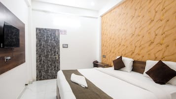 A hotel room with a bed, a TV mounted on the wall, a door, and a wall with a textured pattern.