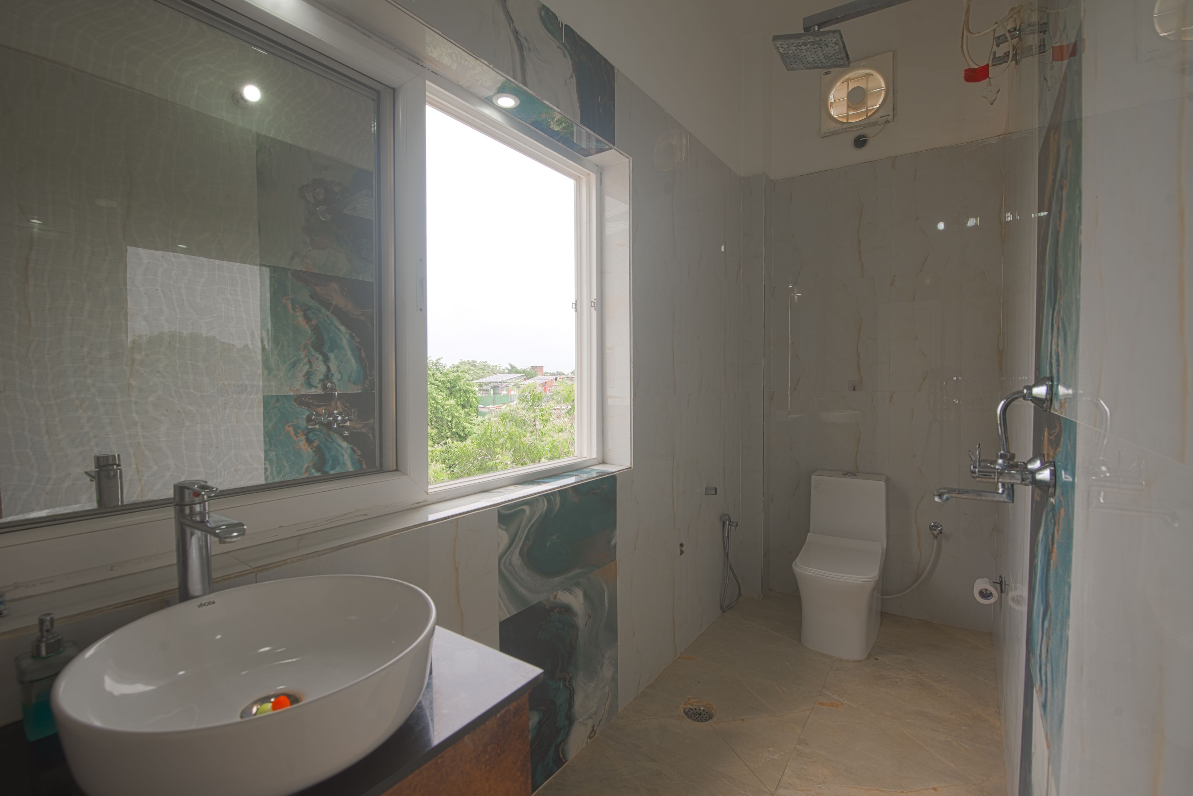 Ein Badezimmer mit großem Fenster, Waschbecken, Toilette und Dusche.