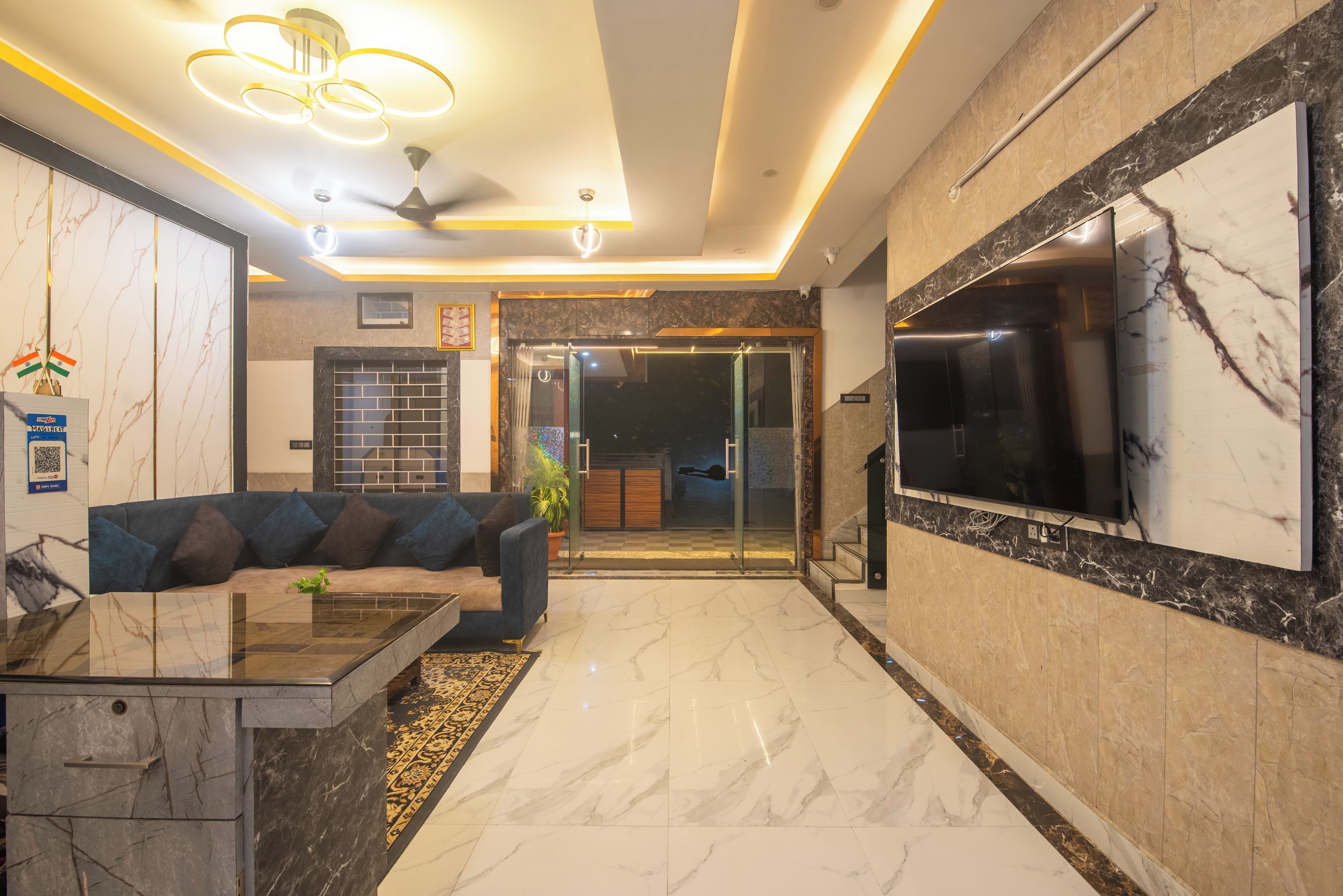 A modern hotel lobby with a sofa, a coffee table, and a TV.