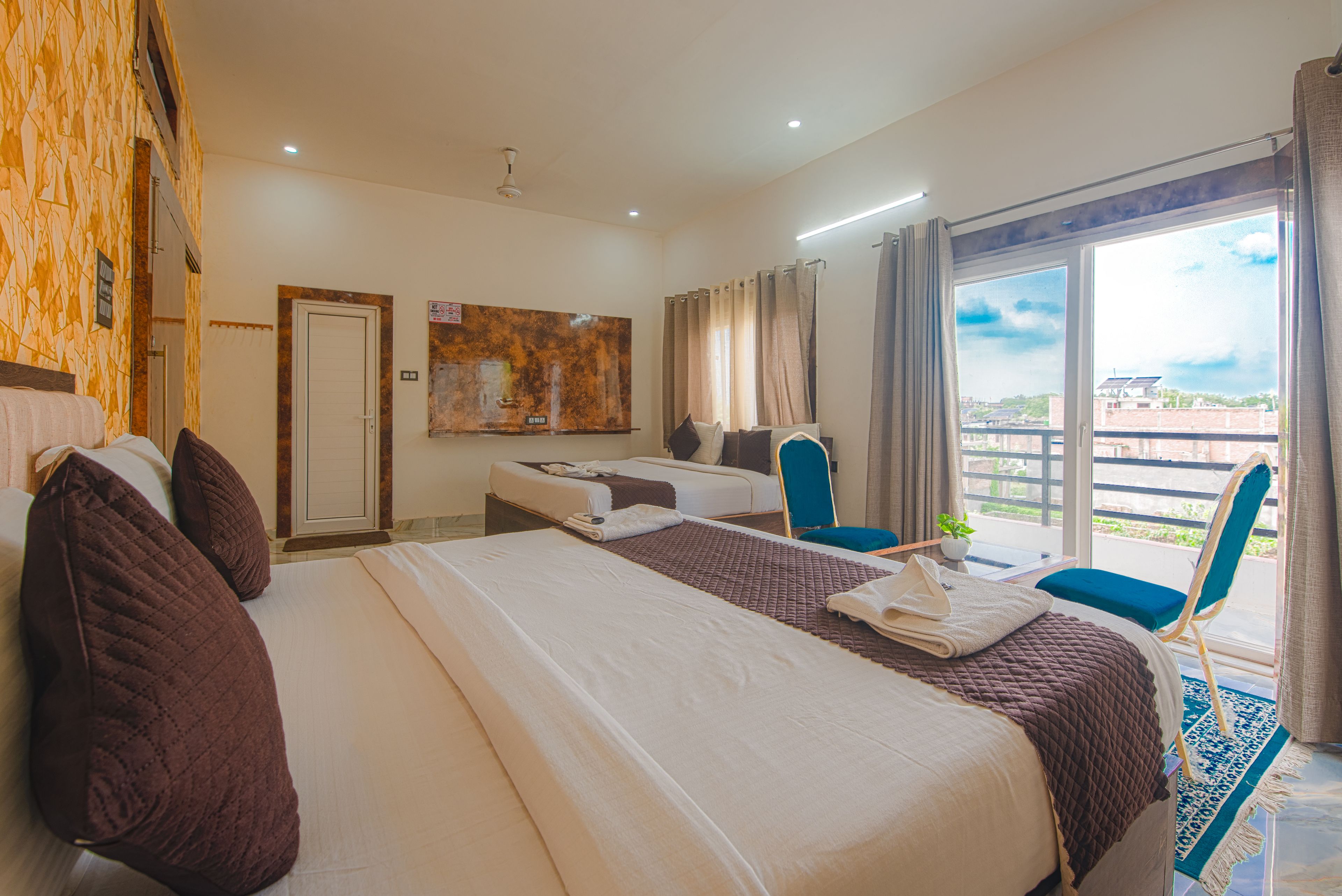 Habitación de hotel con dos camas, un escritorio, una silla y un ventanal con vistas.