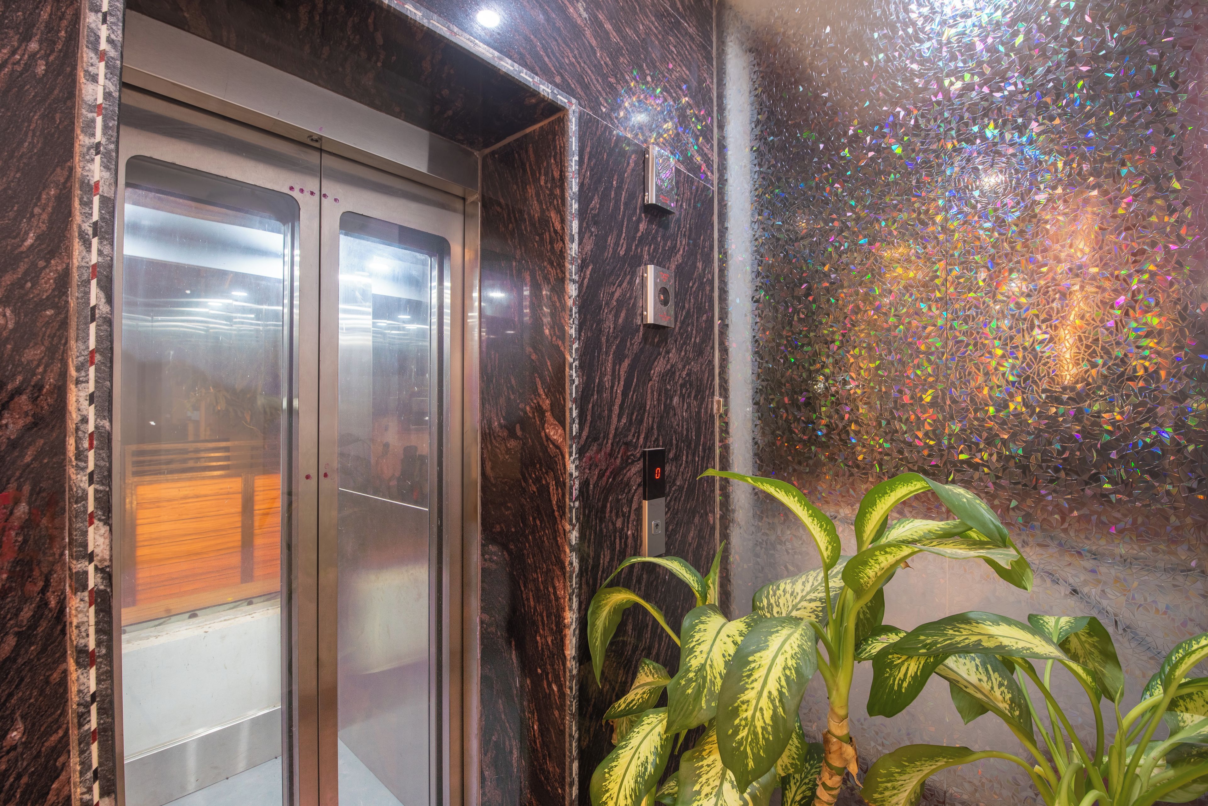 Un ascensor con interior metálico y una pared con textura holográfica.