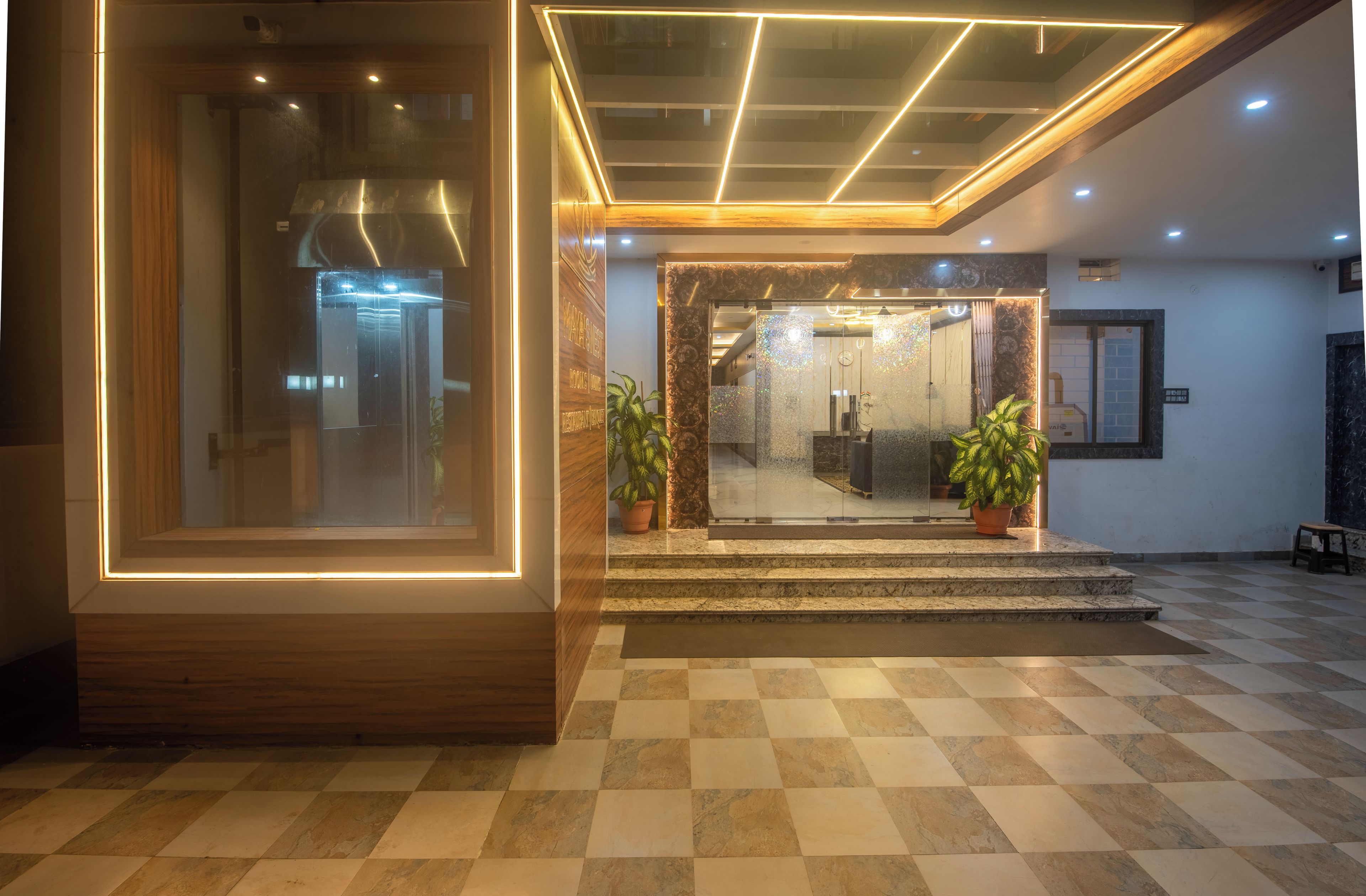 A hotel lobby with a checkered floor, a reception desk, and potted plants.