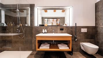Un bagno moderno con cabina doccia in vetro, un mobile vanitario in legno con lavabo bianco e un water bianco.