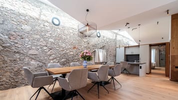 Ein stilvoller Essbereich mit Steinwand, Holztisch und grauen Stühlen.