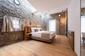 A bedroom with a stone wall, wooden bed, and a skylight.