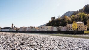 A riverside town with historic buildings, a prominent tower, and a rocky riverbed. - Hotel Traube Rattenberg (Rattenberg)