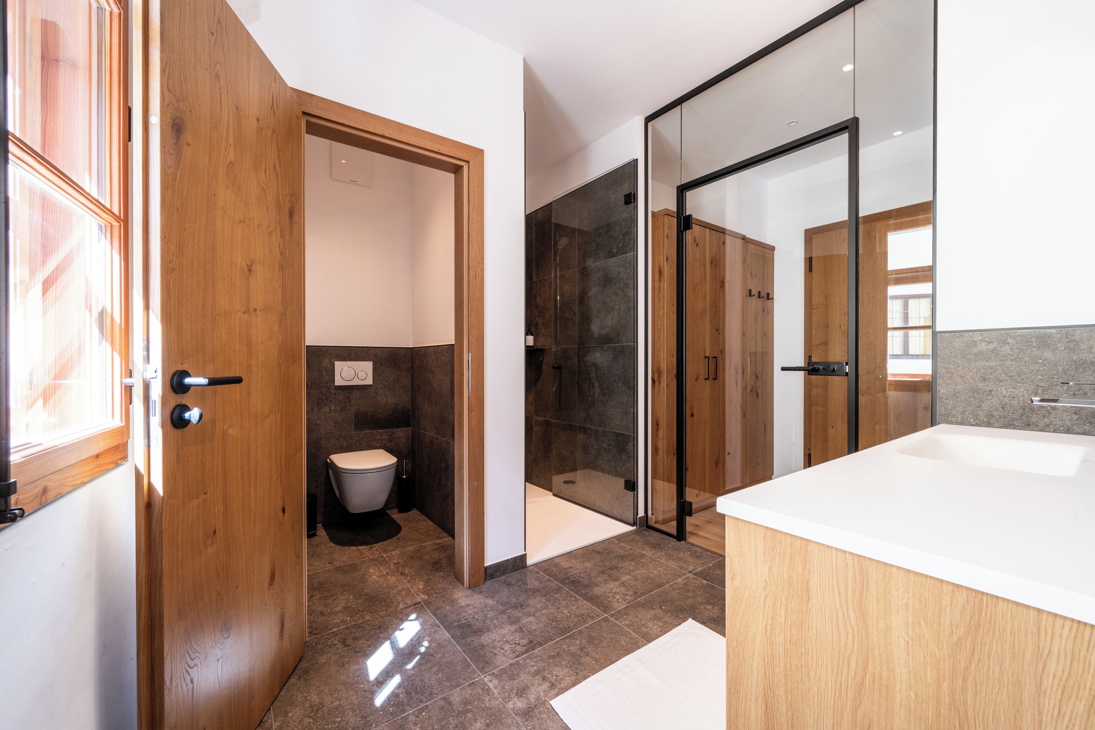 Un baño moderno con puerta de madera, zona de ducha y bañera.