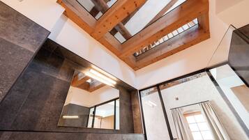 A modern bathroom with a skylight, large mirror, and dark tiles.