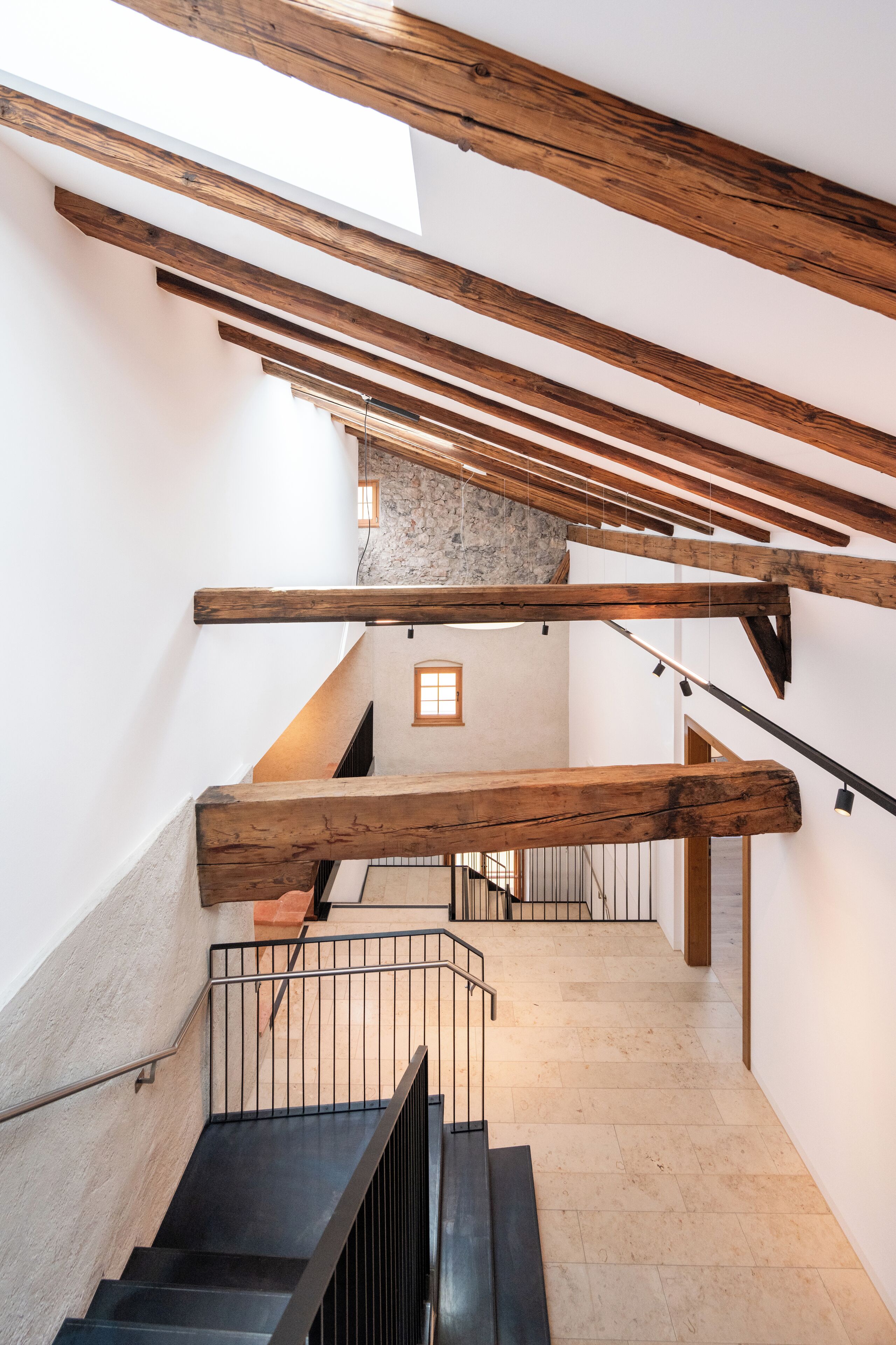 A staircase with wooden beams and a stone wall.