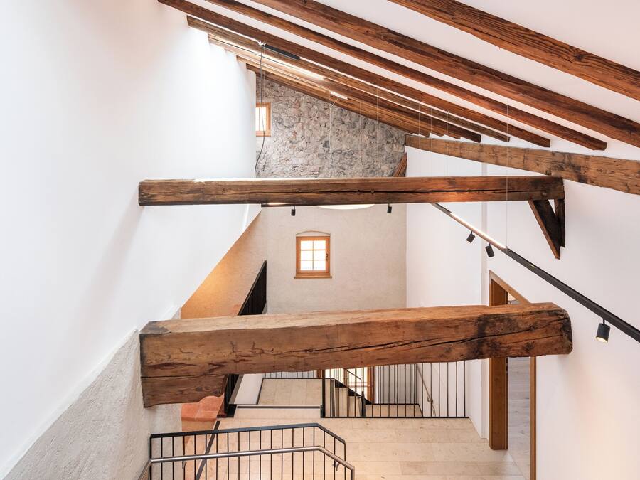 A staircase with wooden beams and a stone wall.