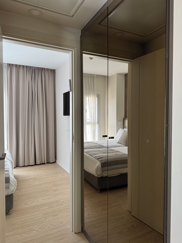 Un dormitorio moderno con una cama grande, un armario y un espejo.