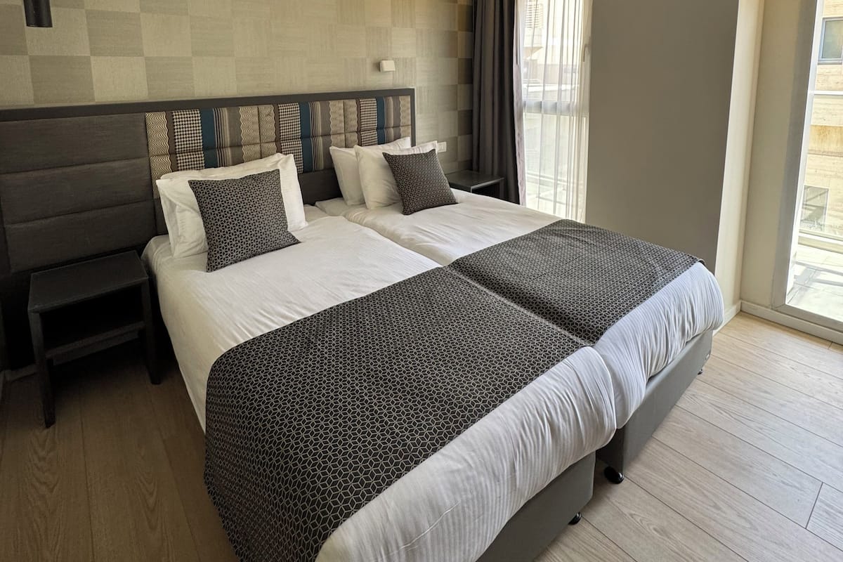 A modern hotel room with a large bed, a bedside table, and a headboard.