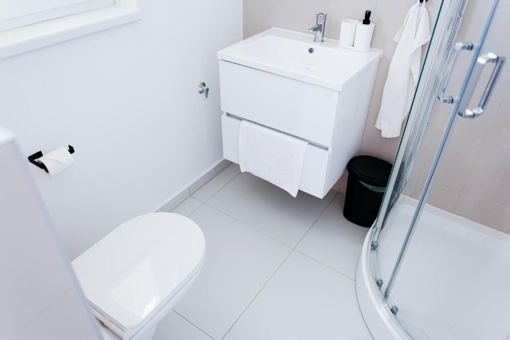 A modern bathroom with a toilet, a sink, and a glass shower enclosure.