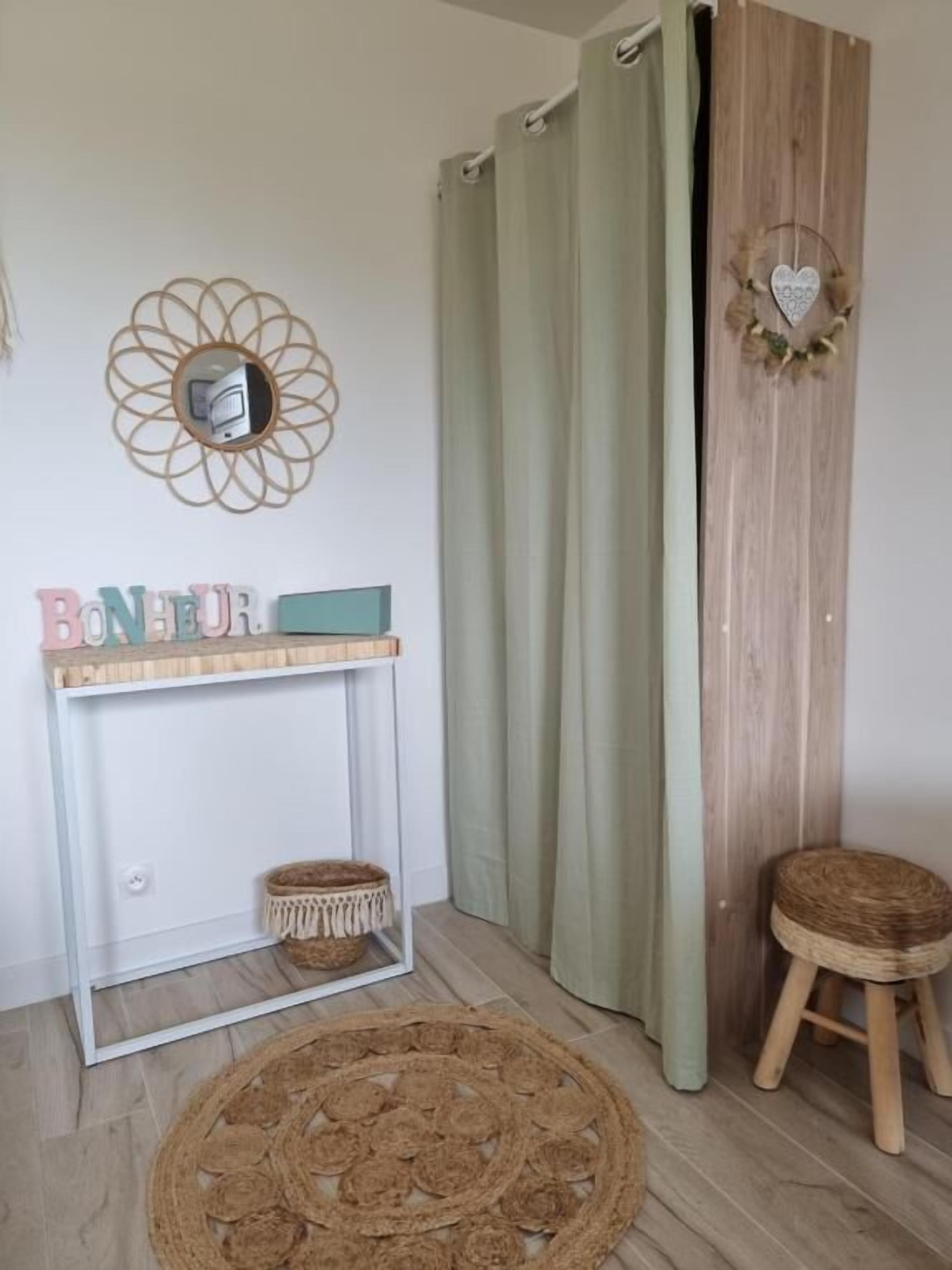 Ein Zimmer mit Holzboden, einem runden Gewebeteppich, einem kleinen Holzschemel, einem Konsolentisch mit Korb und einem Wanddekor.